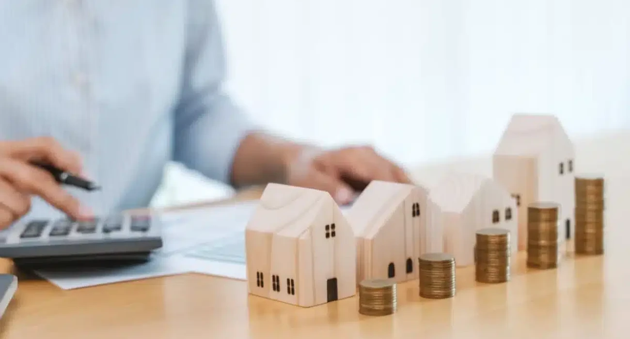 A person calculating property value with a calculator and model houses, determining Indianapolis rent concept