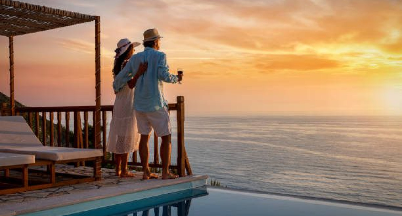 A romantic couple on summer vacation enjos the sunset over the mediterranean sea by the pool with a glass of Aperitif