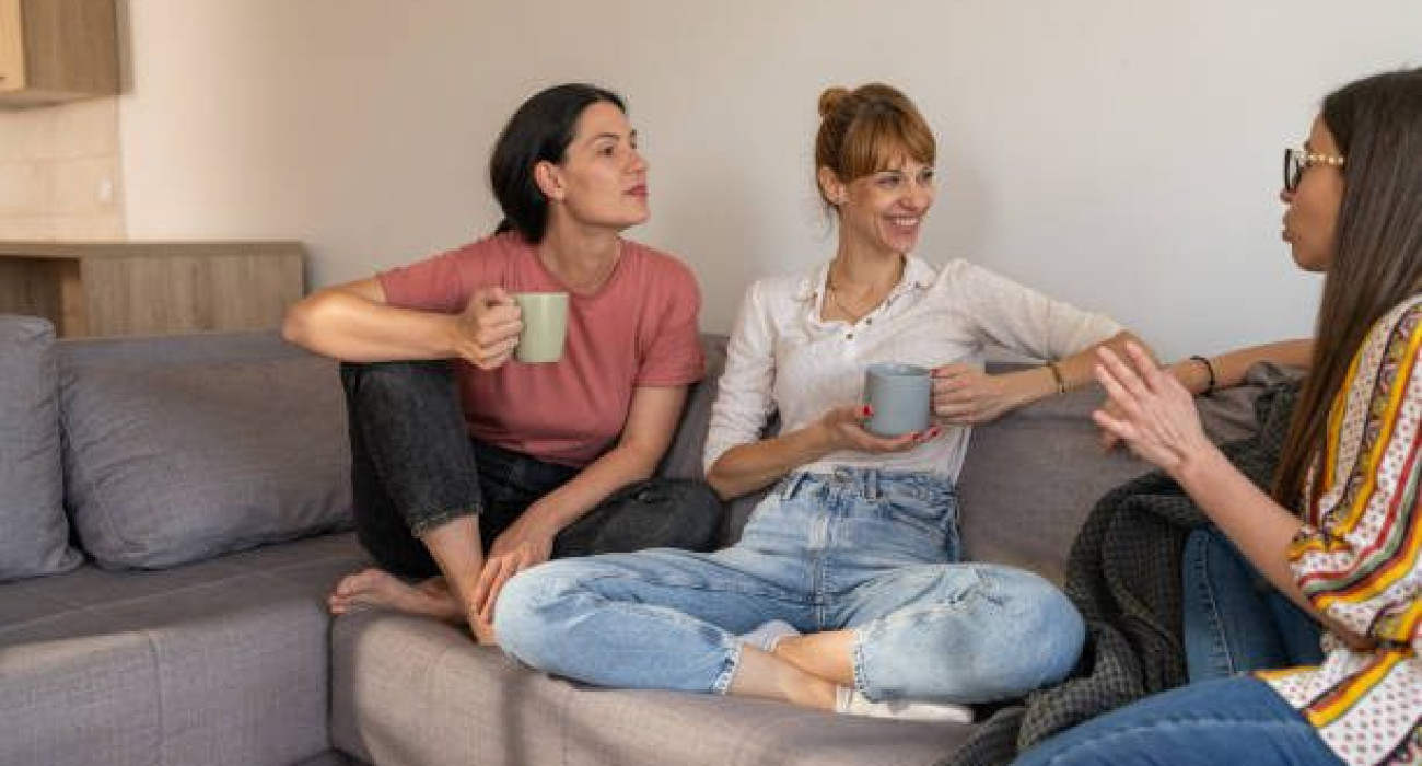 Female friends talking while sitting in living room at home.