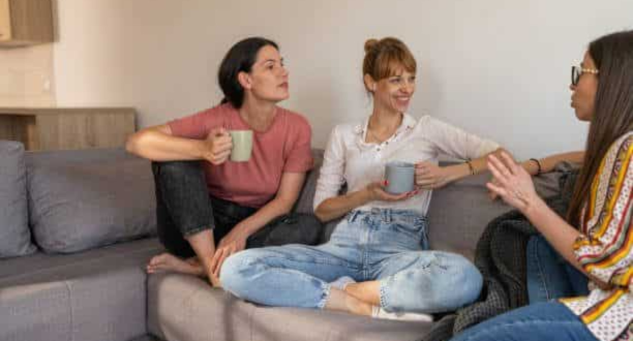 Female friends talking while sitting in living room at home.